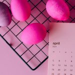 Colorful Easter eggs on a rack and an April 2021 calendar, symbolizing spring celebration.