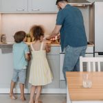 Father and children cooking together in a modern kitchen, enjoying family time.